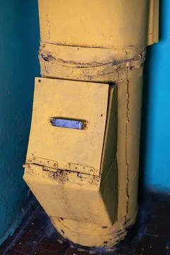 A weathered garbage chute stands in the corner of an old, neglected building. Stock Photos