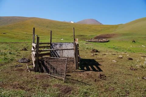 Weathered gate in open field with rolling hills and distant mountains Stock Photos