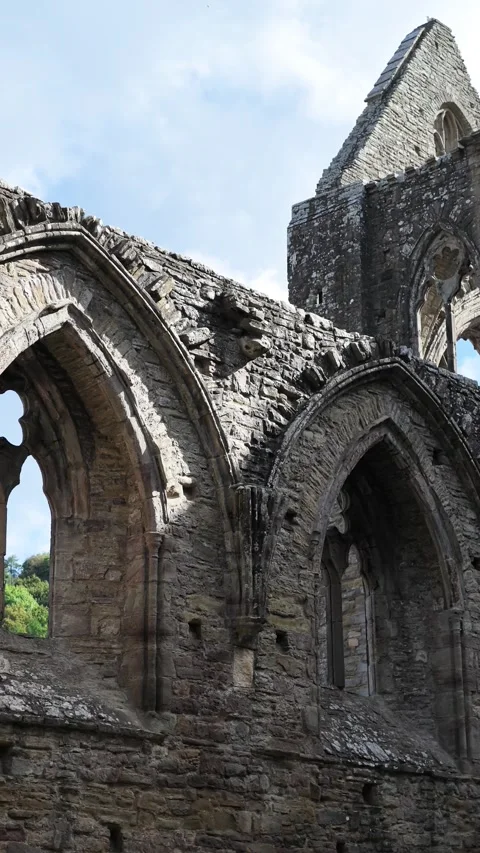 Weathered Gothic window arches of Tintern Abbey church nave as the shot gently Stock Footage 345883944