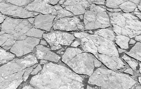 A weathered gray stone pavement of irregular slabs, black and white Stock Photos