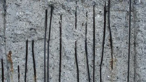 A weathered grey concrete wall through which the rusted steel bars of the f.. Stock Photos