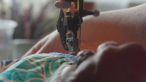 Weathered Hands Guide Patterned Fabric Through Sewing Machine Stock Footage 336717800
