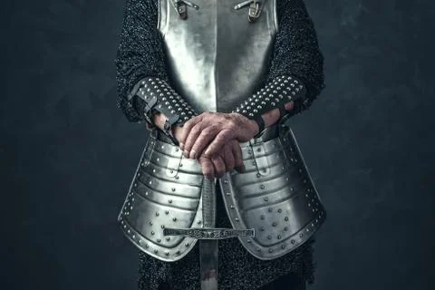 Weathered hands of knight holding sword. Stock Photos