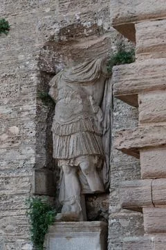 Weathered headless stone statue set in the wall at a historic castle entran.. Stock Illustration