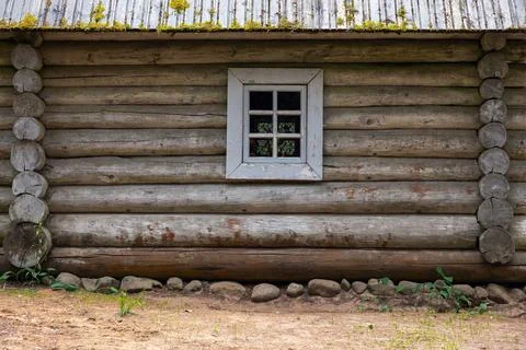 Weathered horizontal logs and a small white-framed window on a rustic cabin.. Stock Photos