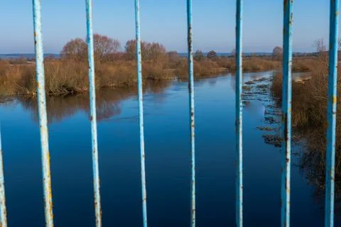 Weathered light blue bridge railing frames wide river and leafless banks Stock Photos