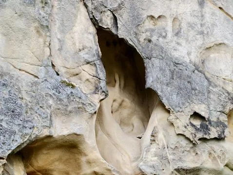 Weathered limestone cliff with eroded cavity and textured rock surfaces Stock Photos