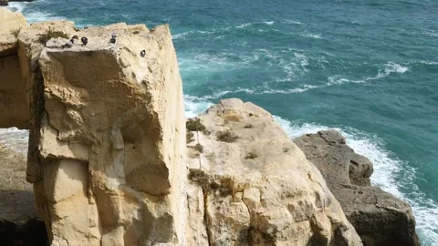 Weathered limestone cliff face rises above swirling sea rock texture close wave Stock Footage 341799944
