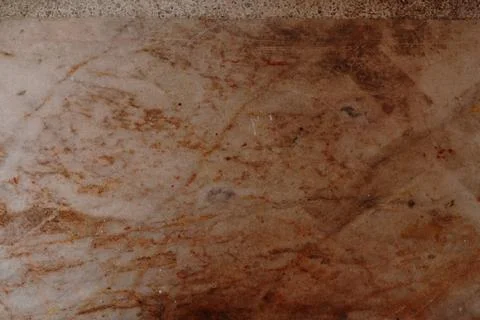 Weathered marble surface with brown veining and scattered debris 스톡 사진