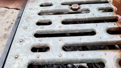 Weathered Metal Drainage Grate with Rust and Dirt on Urban Pavement Surface 스톡 동영상 346677892