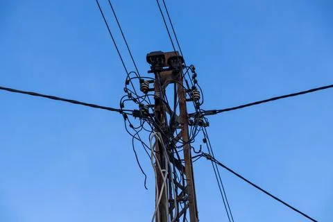 A weathered metal utility pole supporting a complex network of tangled Stock Photos