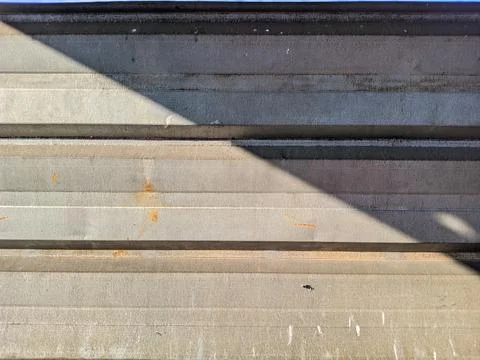 Weathered Metal Wall Texture with Rust Stains and Strong Sunlight Shadows 库存照片