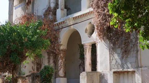 Weathered neoclassical villa facade with columns and a carved pediment, seen Vidéo 344898827