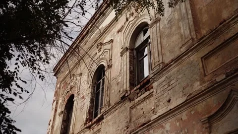 Weathered old building facade with arched windows and tree branches 動画素材 347535780