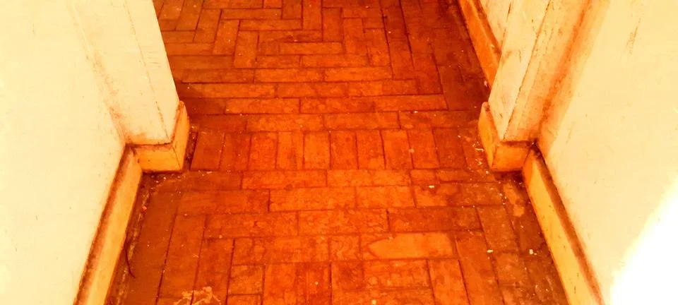 Weathered orange brick floor inside a narrow old residential hallway passage Stock Photos