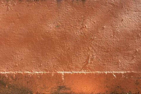 A weathered orange cement wall texture showing rough surface details Stock Photos
