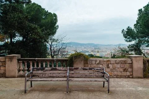 Weathered park bench offers panoramic view of Barcelona cityscape on an ove.. Stock Photos