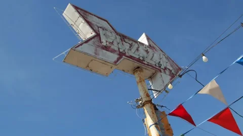 Weathered pizza arrow sign with triangular pennant banner. 4k60p Stock Footage 133375675