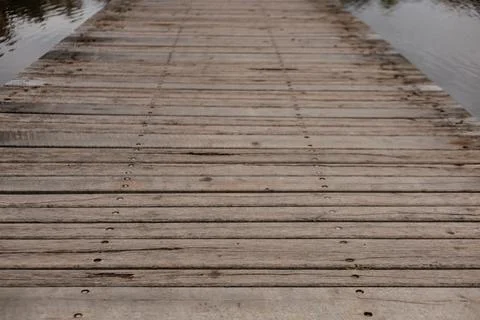 Weathered planks stretch out over serene water Stock Photos
