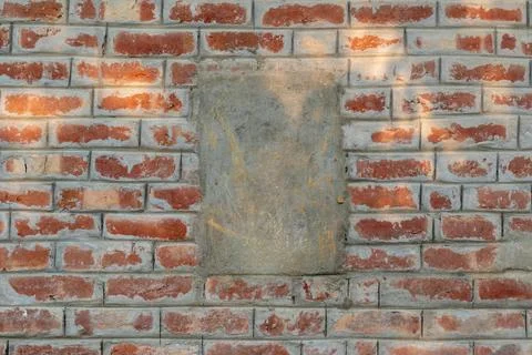 Weathered red brick wall featuring a large central gray patch of smooth dri.. Stock-Fotos