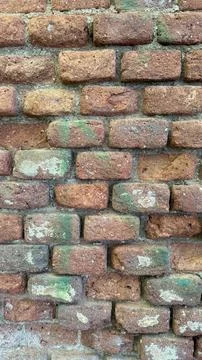 Weathered red brick wall featuring rough textures, mortar joints, and patches Stock Photos