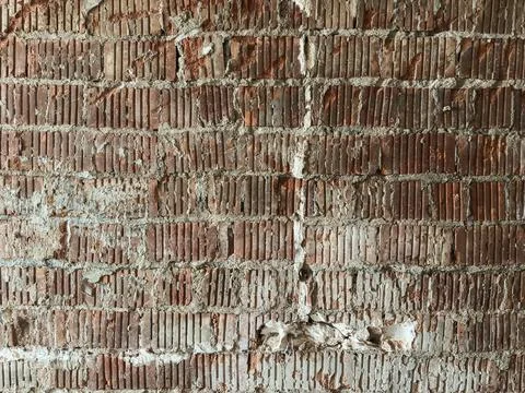 Weathered red brick wall with peeling white plaster, cracks, and subtle disco Stock Photos