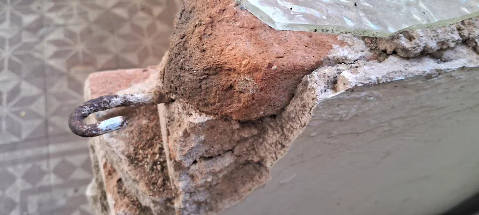 Weathered red brick wall with a rusted metal hook attachment Stock Photos