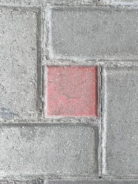 Weathered Red Square Paving Block Among Grey Concrete Pavers Stock Photos