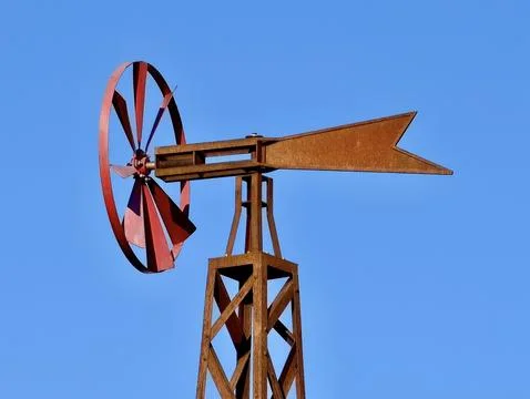 Weathered red windmill rotor with rusted tail mounted on lattice tower agai.. Stock Photos