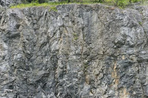 Weathered rock face texture in old stone pit with parts of green. Fotos de archivo