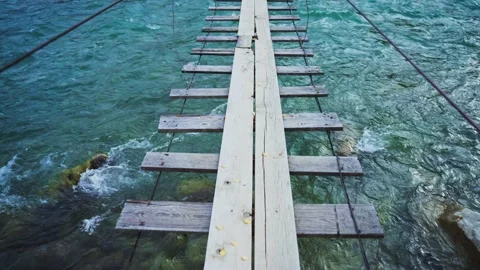 Weathered rope bridge crosses wild, foamy water Stock Footage 342736877