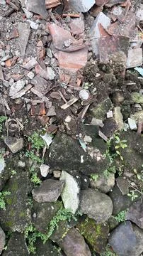 Weathered rubble with moss growing between rocks and shattered bricks creatin Stock Photos