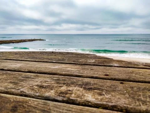 Weathered rustic wooden table top foreground with blurry ocean waves, a coast 库存照片