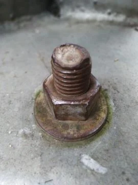 Weathered rusty bolt, nut, and washer on a textured concrete surface Stock Photos