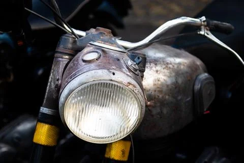 Weathered rusty vintage motorcycle front view with aged headlight and fuel ta Stock Photos