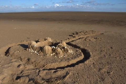 A weathered sand castle on an empty beach. Stock Photos