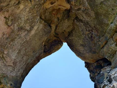 Weathered sandstone arching overhead, framing clear blue sky from below wit.. Stock Photos