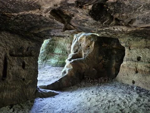 Weathered sandstone cave interior with eroded ceiling, sculpted pillars, sa.. Stock Photos