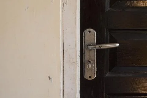 A weathered silver door handle and key ring mounted on a dark wooden door, .. Stock Photos