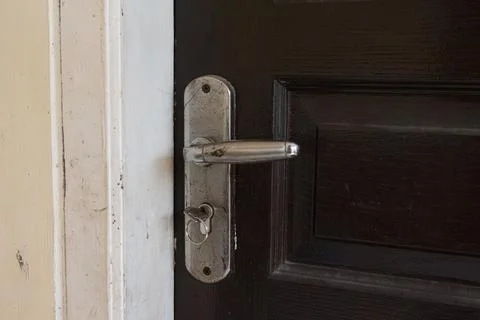 A weathered silver door handle and key ring mounted on a dark wooden door, .. Photos