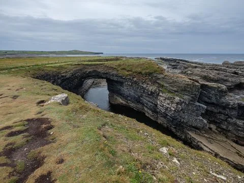 Weathered stone arch frames sea beyond Stock-Fotos