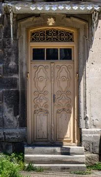 Weathered stone archway frames a vintage wooden door with decorative panels Stock Photos