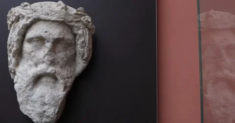 Weathered stone bearded head sculpture on dark wall at the British Museum Stock Footage 321020105