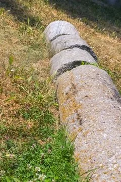 Weathered stone cylinders lying in grass rustic archaeological detail with .. Stockfoto's