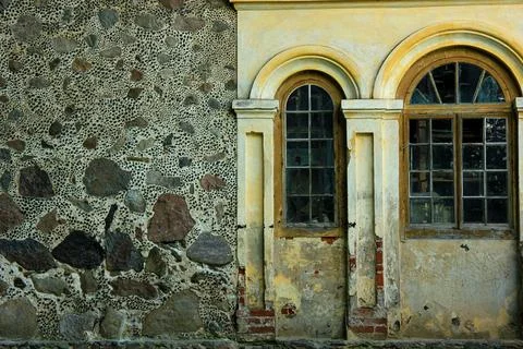 Weathered stone facade with arched windows and peeling plaster on historic .. Fotos de archivo