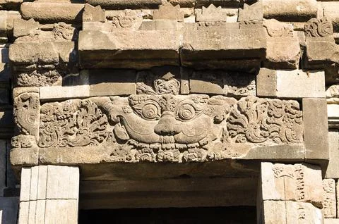 Weathered stone lintel features intricate Hindu relief carvings above an en.. Photos