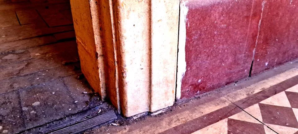 Weathered stone pillar corner with rustic red marble wall texture Foto stock