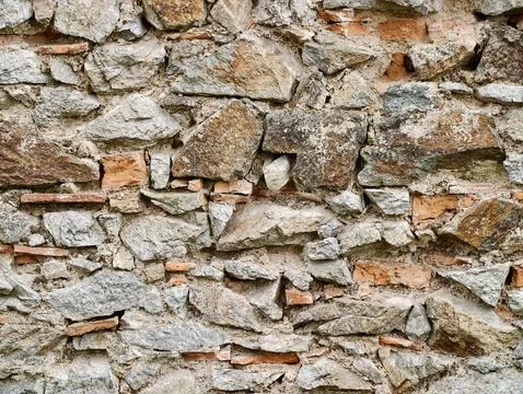 Weathered stone wall with exposed brick fragments Stock Photos