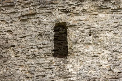 Weathered stone wall featuring a narrow arched window of Izborsk Fortress 写真素材