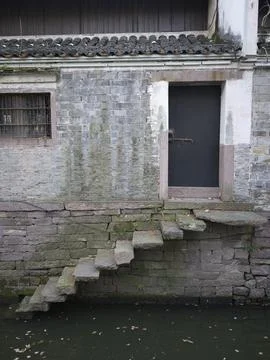 A weathered stone wall with steps over green water, China Stock Photos